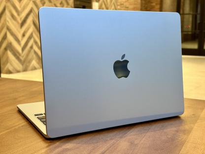 Light blue Apple laptop on a wooden table.