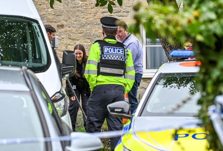 Police officers and forensic investigators at a crime scene in a residential area.