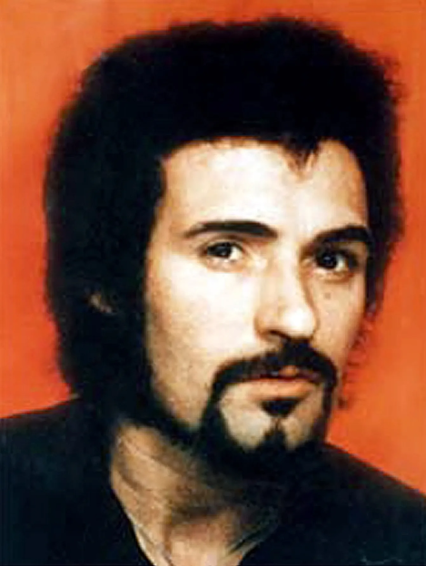 Portrait of a man with dark curly hair and a goatee.