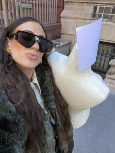 Woman in sunglasses holding a mannequin.