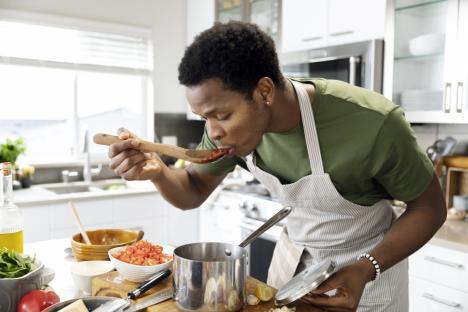 A man tasting sauce while cooking.