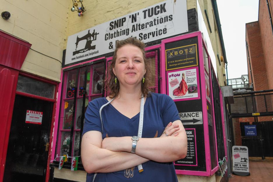 Rachel Prince of Snip 'n' Tuck, a clothing alterations and repair service, standing outside her shop.