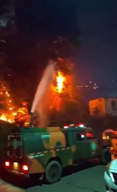 Firefighter spraying water on a large fire during a fireworks performance.