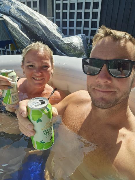 Couple relaxing in a hot tub with cider.