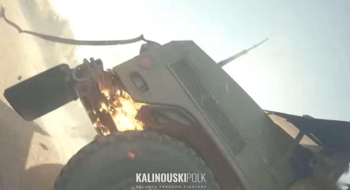 A military vehicle with its top ripped off, engulfed in flames and smoke.