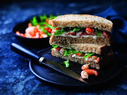 A triple-decker sandwich with shrimp, arugula, and mayonnaise on whole-wheat bread.