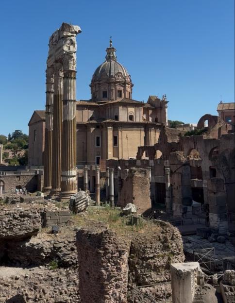 Roman Forum ruins with a church dome in the background.