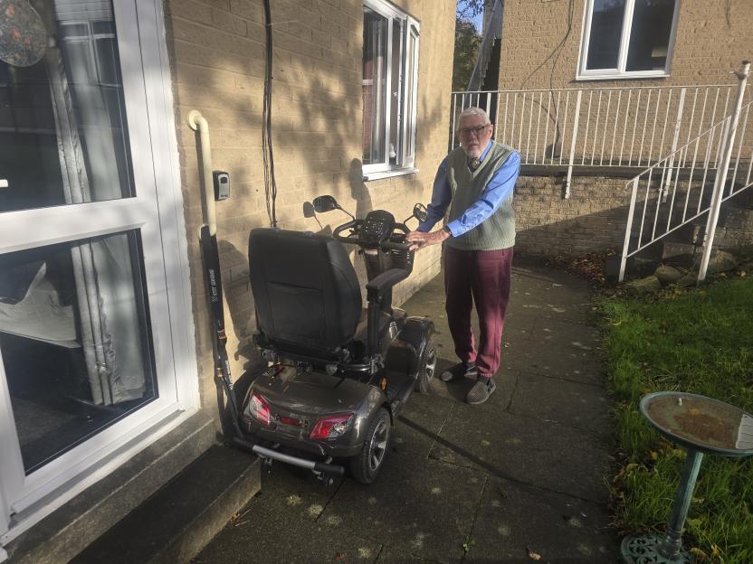 Ron Gibbs, an RAF veteran, stands beside his mobility scooter.