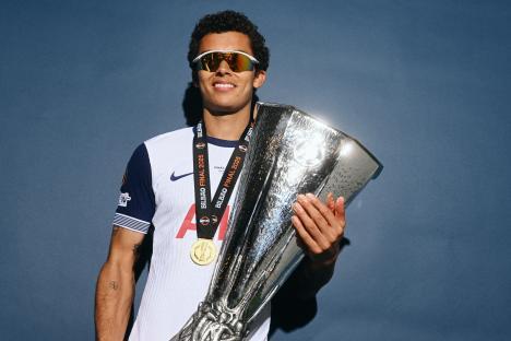 Brennan Johnson of Tottenham Hotspur holding the UEFA Europa League trophy and medal.