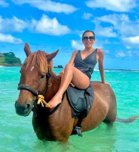 Woman horseback riding in the ocean.
