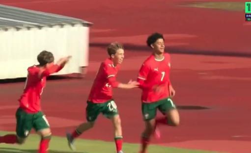 Three soccer players in red and green uniforms celebrating a goal.