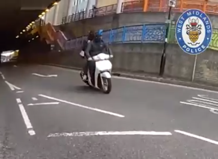 Person on a white scooter driving through a tunnel.