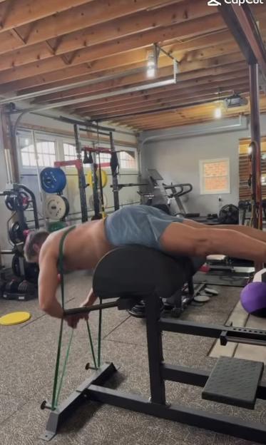 Man doing back extensions with resistance bands in a home gym.