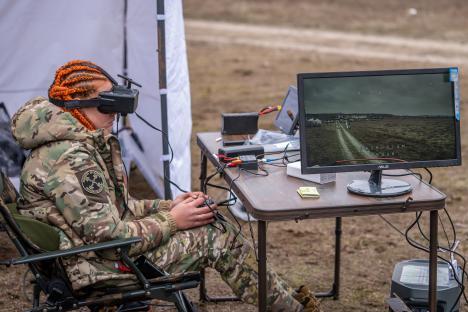 Ukrainian servicewoman using VR headset to operate a drone via fiber optic cable.