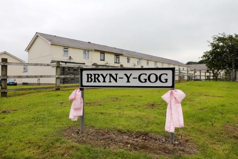 A Bryn-Y-Gog street sign with pink ribbons tied to the posts.
