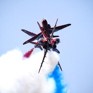 Four Red Arrows jets performing a Roll Back maneuver.