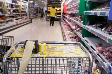 Shopping cart in a supermarket with discarded yellow discount stickers.