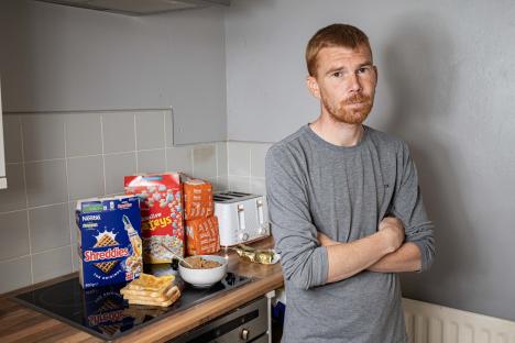 A man with ARFID stands in his kitchen with bread and cereal.