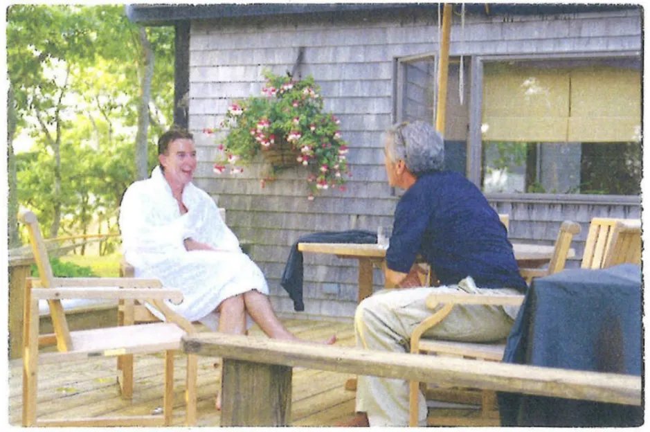 Two people sitting on a deck and talking.