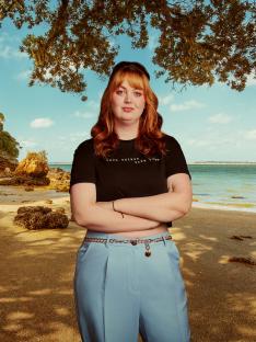 Woman with red hair standing on a beach.
