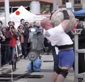 Strongman lifting a large stone.