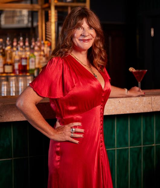Mel Fallowfield in a red dress at a bar.