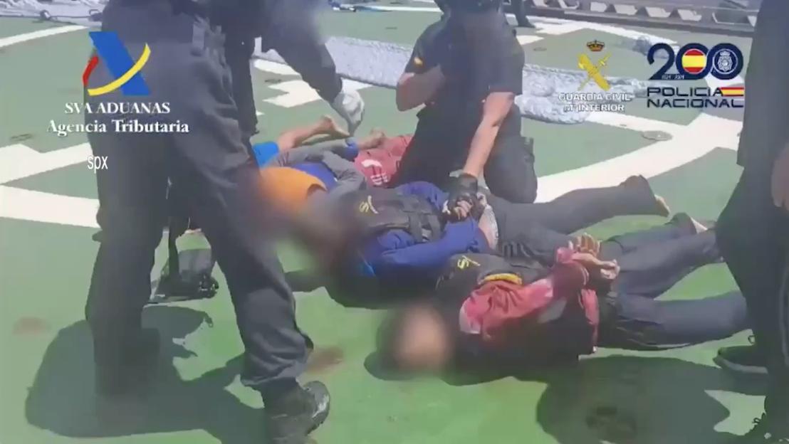 Arrested suspects lying on a ship deck.