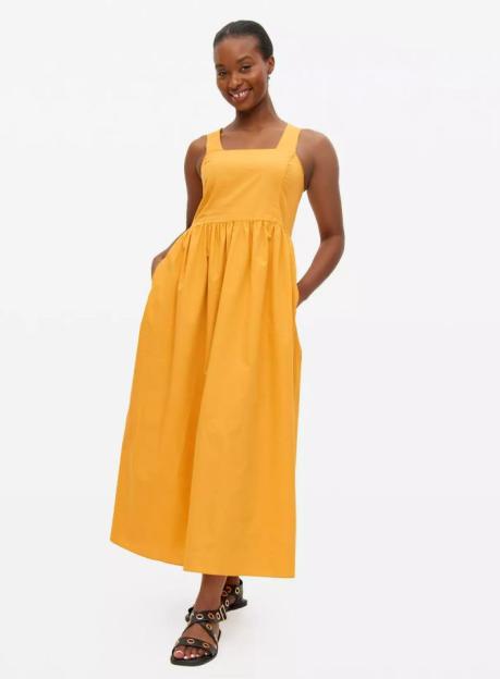 Woman wearing a mustard yellow maxi dress with pockets.