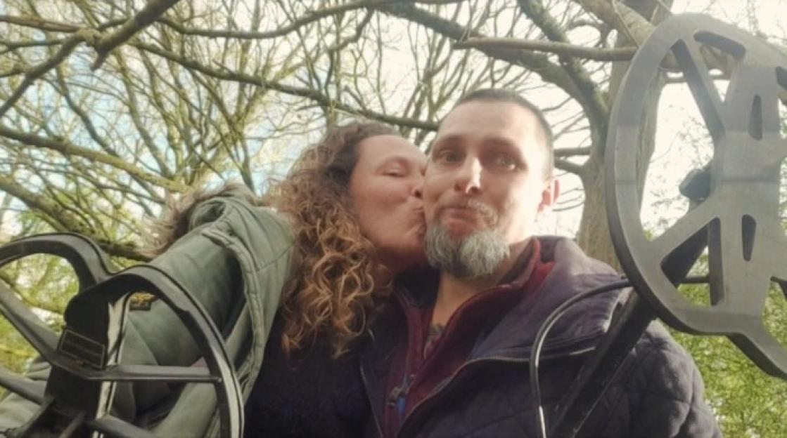 Photo of a couple kissing, holding metal detectors.