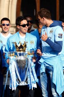 Manchester City players celebrating with the Premier League trophy.