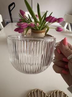 A hand holding a ribbed glass mug.