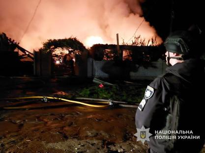 Burning building in Pryluky, Chernihiv region, with a police officer in the foreground.