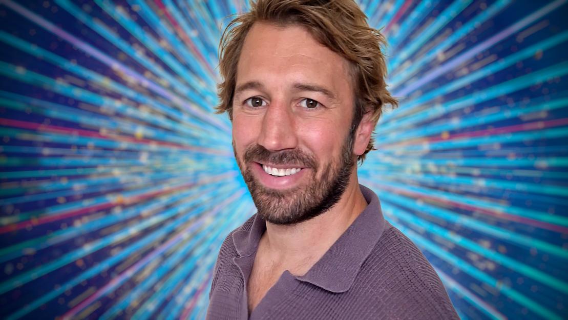 A man smiling against a sparkly background.