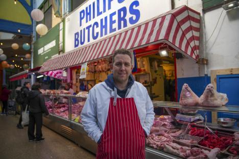Butcher standing in his shop at Brixton Market.