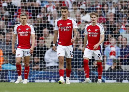 Three Arsenal soccer players stand dejectedly by the goal.