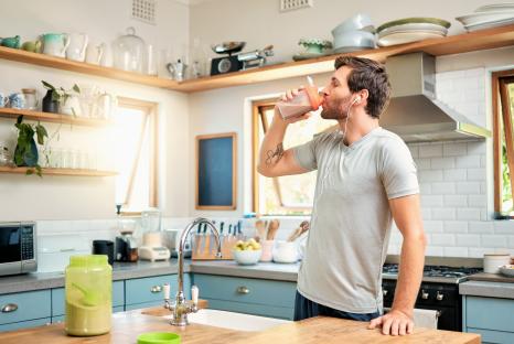 Man drinking protein shake in his kitchen.