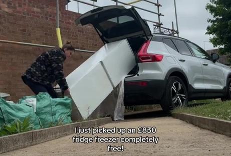 Person loading a free fridge-freezer into their car.