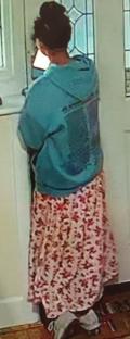 Image of a woman wearing a teal hoodie and a long pink and red patterned skirt.
