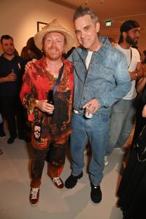 Leigh Francis and Robbie Williams at an art exhibition.
