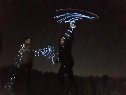 Photo of two sisters at night, using light painting to create abstract shapes.
