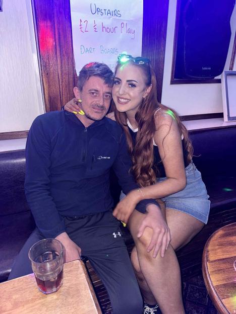 A man and a woman sitting on a booth in a bar.