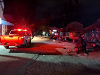 Nighttime scene of a street with police vehicles and people after a stabbing incident.