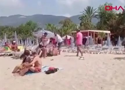 A person being attacked on a busy beach.