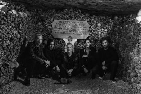 Black and white photo of Queens of the Stone Age in the Paris catacombs.