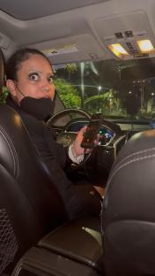 A frightened woman in a car uses her phone to call emergency services.