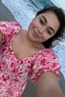 Woman in pink floral dress at the beach.