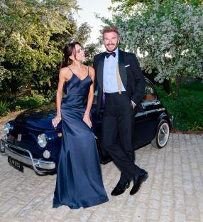 David and Victoria Beckham posing by a classic car.