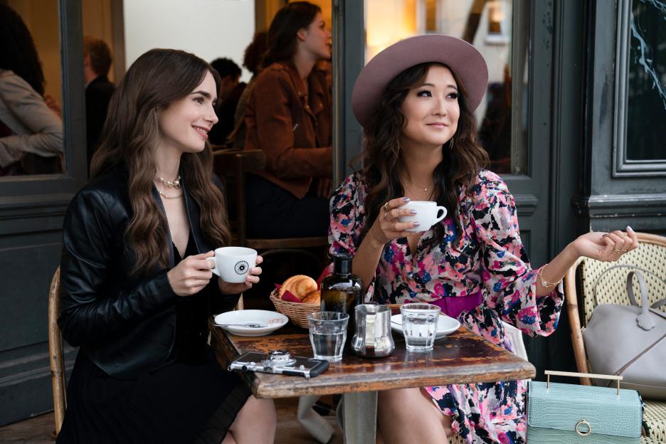 Mindy Chen and Emily Cooper sitting at a cafe table with coffee.