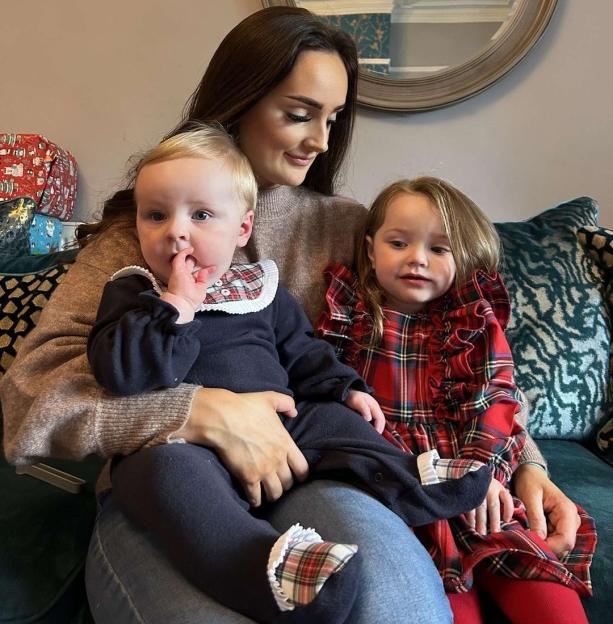 Woman holding two young children.
