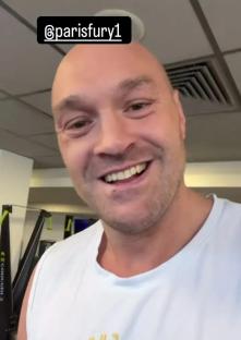 Tyson Fury in a gym, smiling at the camera.